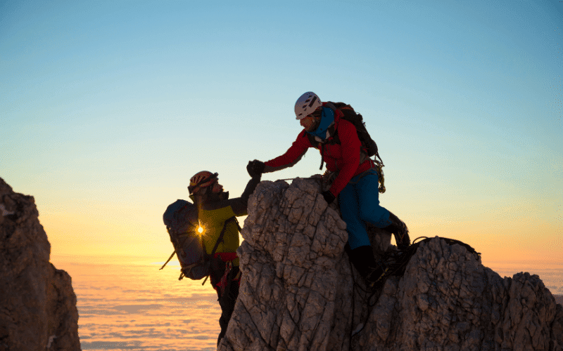 A group of young climbers tackle a challenging rock wall, their ropes and gear strewn about as they ascend with determination